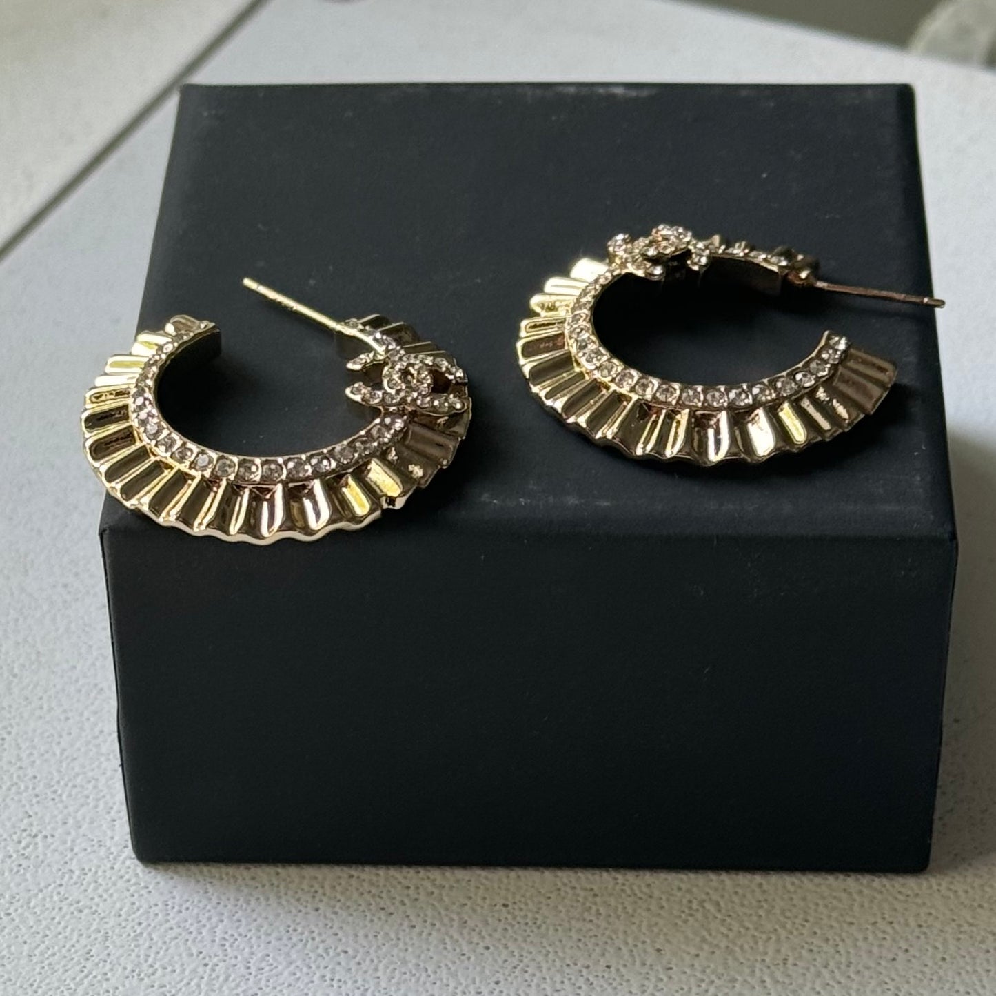 Gold Plated Chanel Flatten Hoops with Crystals Post EarringsStunning ! Gold Plated Bigger Hoops with great head turning texture with clear crystals accented along the inner side of these Double C Post Earrings Comes with the Chanel Box & Bag In clean grea