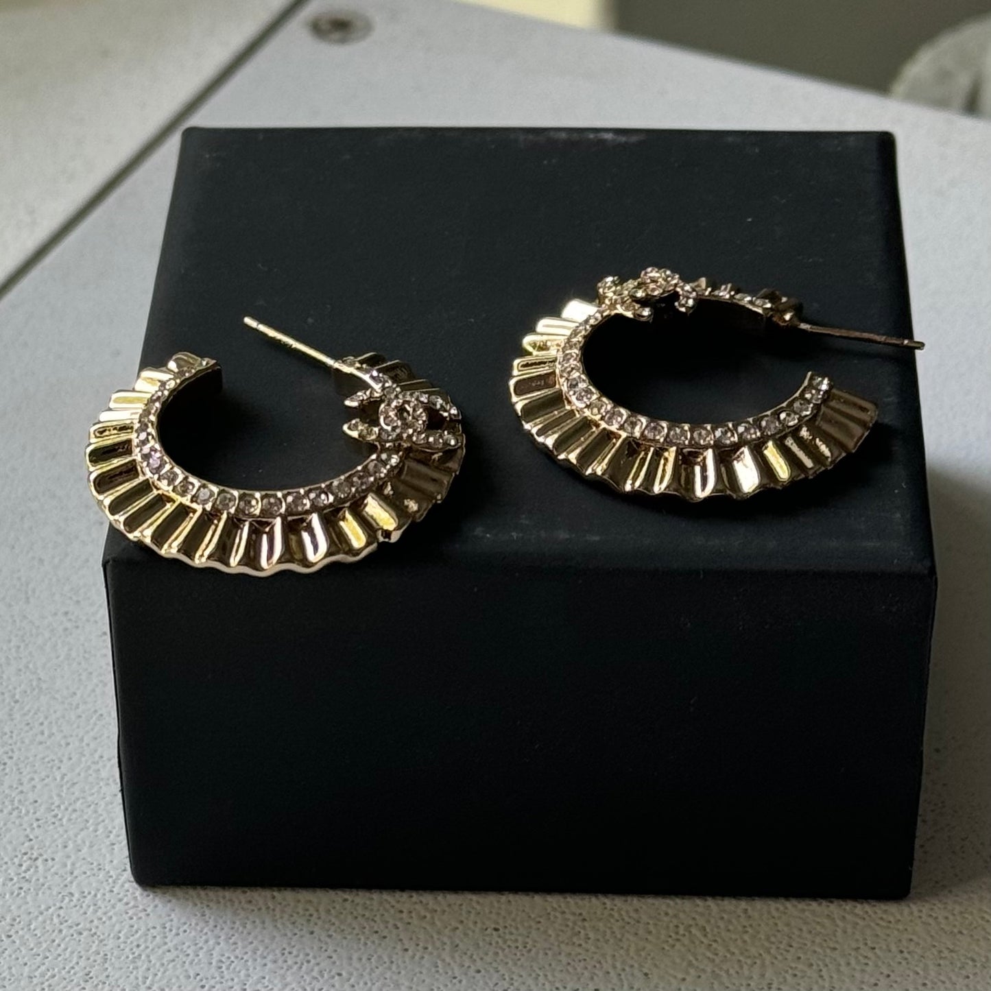 Gold Plated Chanel Flatten Hoops with Crystals Post EarringsStunning ! Gold Plated Bigger Hoops with great head turning texture with clear crystals accented along the inner side of these Double C Post Earrings Comes with the Chanel Box & Bag In clean grea