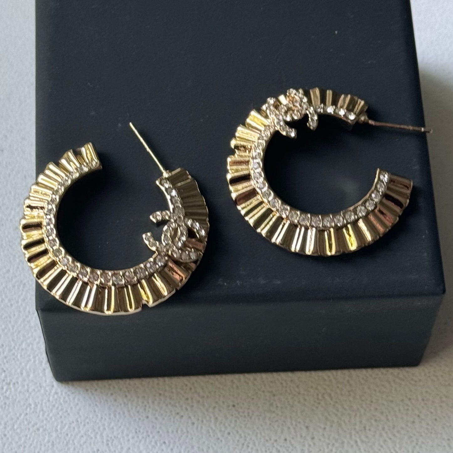 Gold Plated Chanel Flatten Hoops with Crystals Post EarringsStunning ! Gold Plated Bigger Hoops with great head turning texture with clear crystals accented along the inner side of these Double C Post Earrings Comes with the Chanel Box & Bag In clean grea