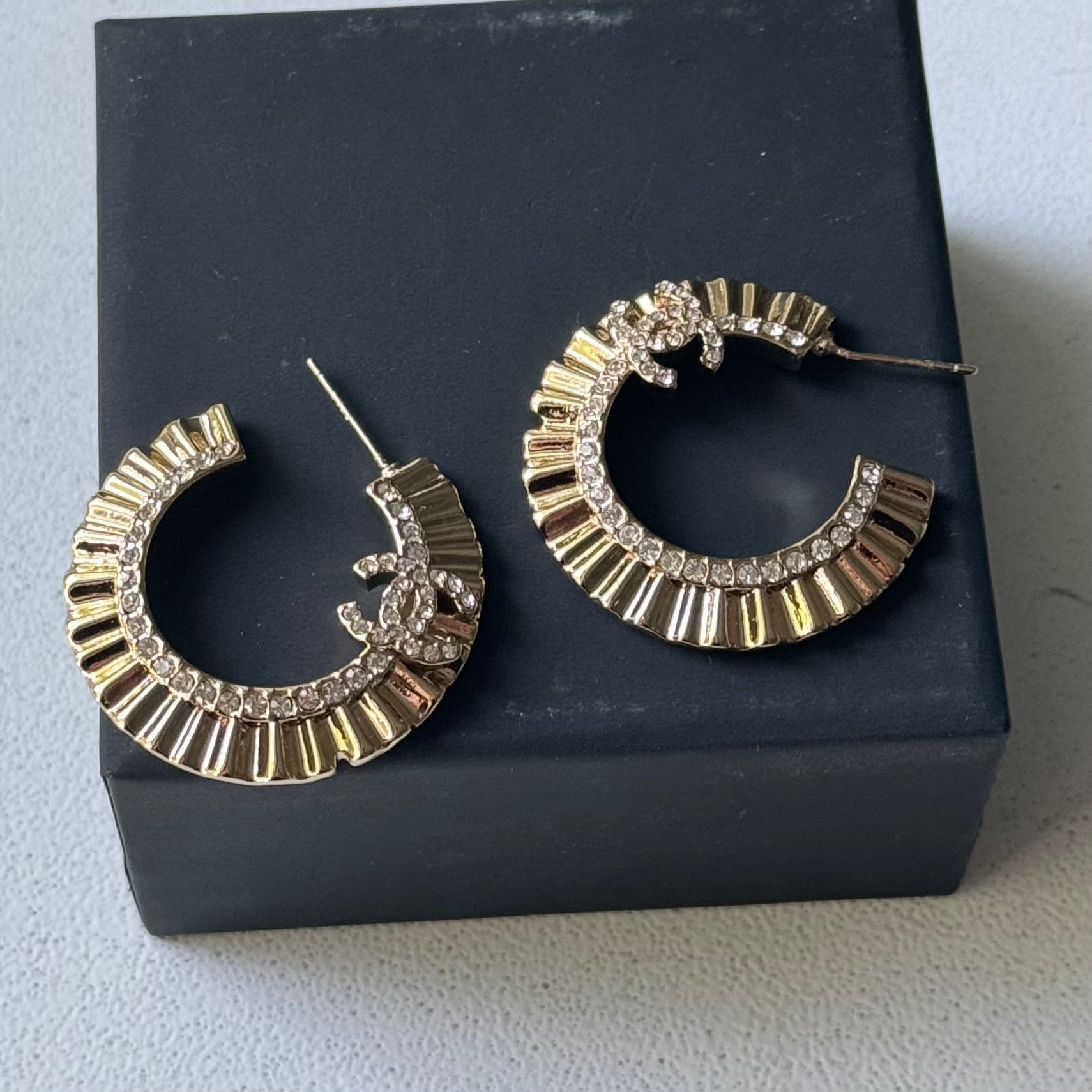 Gold Plated Chanel Flatten Hoops with Crystals Post EarringsStunning ! Gold Plated Bigger Hoops with great head turning texture with clear crystals accented along the inner side of these Double C Post Earrings Comes with the Chanel Box & Bag In clean grea