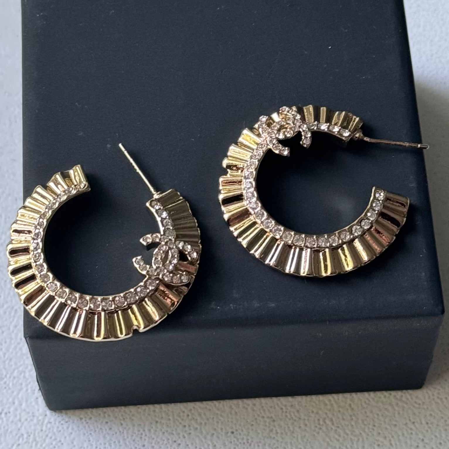 Gold Plated Chanel Flatten Hoops with Crystals Post EarringsStunning ! Gold Plated Bigger Hoops with great head turning texture with clear crystals accented along the inner side of these Double C Post Earrings Comes with the Chanel Box & Bag In clean grea