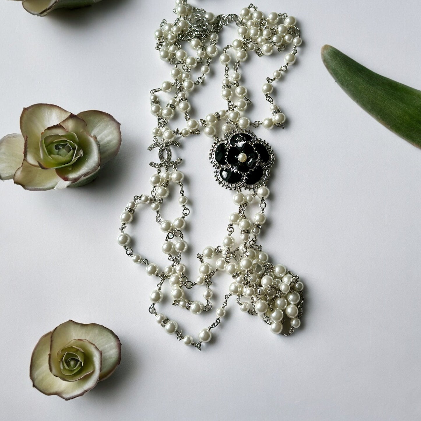 Chanel Pearl Camila Enamel Flower Three Strand NecklaceGorgeous Authentic Chanel Triple Strand (faux) Pearl linked with silver wiring , Double C with crystals Link , Black with silver accents enamel Camila Flower Focal Point Charm Lobster Safety Clasp Mar