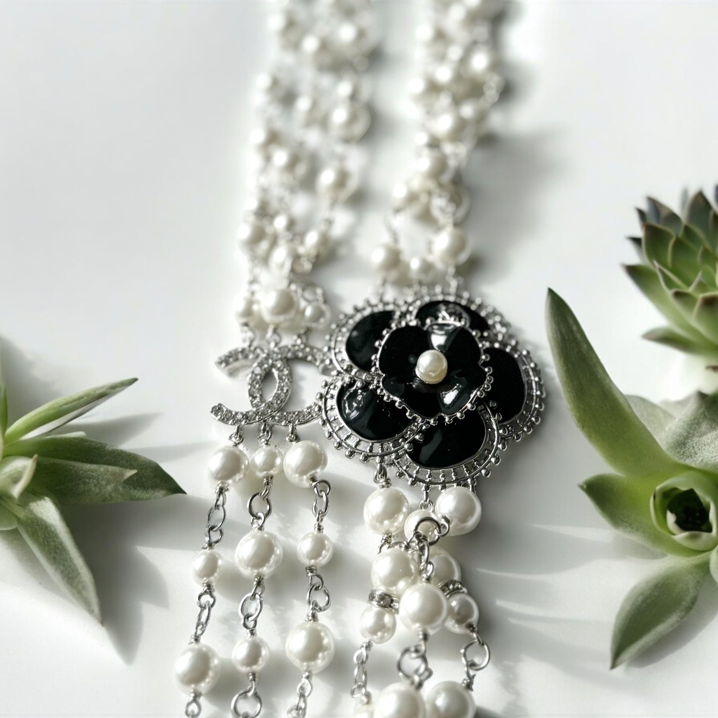 Chanel Pearl Camila Enamel Flower Three Strand NecklaceGorgeous Authentic Chanel Triple Strand (faux) Pearl linked with silver wiring , Double C with crystals Link , Black with silver accents enamel Camila Flower Focal Point Charm Lobster Safety Clasp Mar