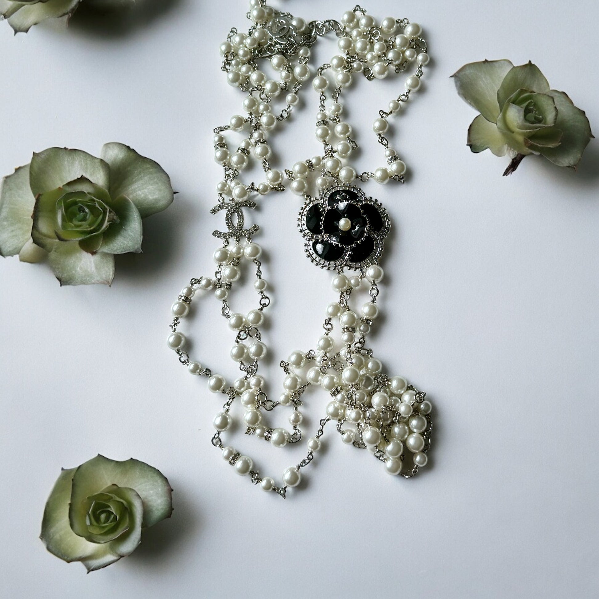 Chanel Pearl Camila Enamel Flower Three Strand NecklaceGorgeous Authentic Chanel Triple Strand (faux) Pearl linked with silver wiring , Double C with crystals Link , Black with silver accents enamel Camila Flower Focal Point Charm Lobster Safety Clasp Mar