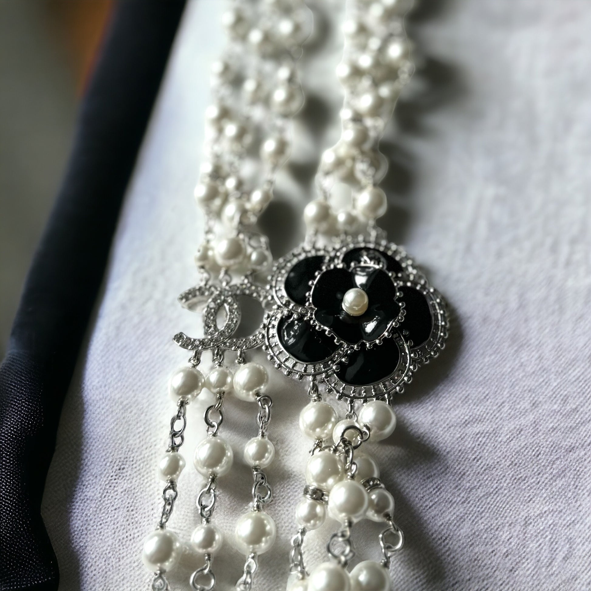 Chanel Pearl Camila Enamel Flower Three Strand NecklaceGorgeous Authentic Chanel Triple Strand (faux) Pearl linked with silver wiring , Double C with crystals Link , Black with silver accents enamel Camila Flower Focal Point Charm Lobster Safety Clasp Mar