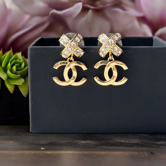 Chanel Gold Double C Dangle Earrings with Crystal Encrusted X’s Post EarringsAdd a touch of understated elegance to any outfit with Chanel's Gold Double C Dangle Earrings. Crystal encrusted X's add a statement touch to these comfortable post earrings. Per My Mama Found What 